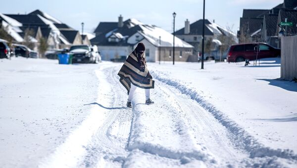 A man walks to his friend's home in a neighbourhood without electricity as snow covers the BlackHawk neighborhood in Pflugerville, Texas, U.S. February 15, 2021. Picture taken February 15, 2021 - Sputnik International