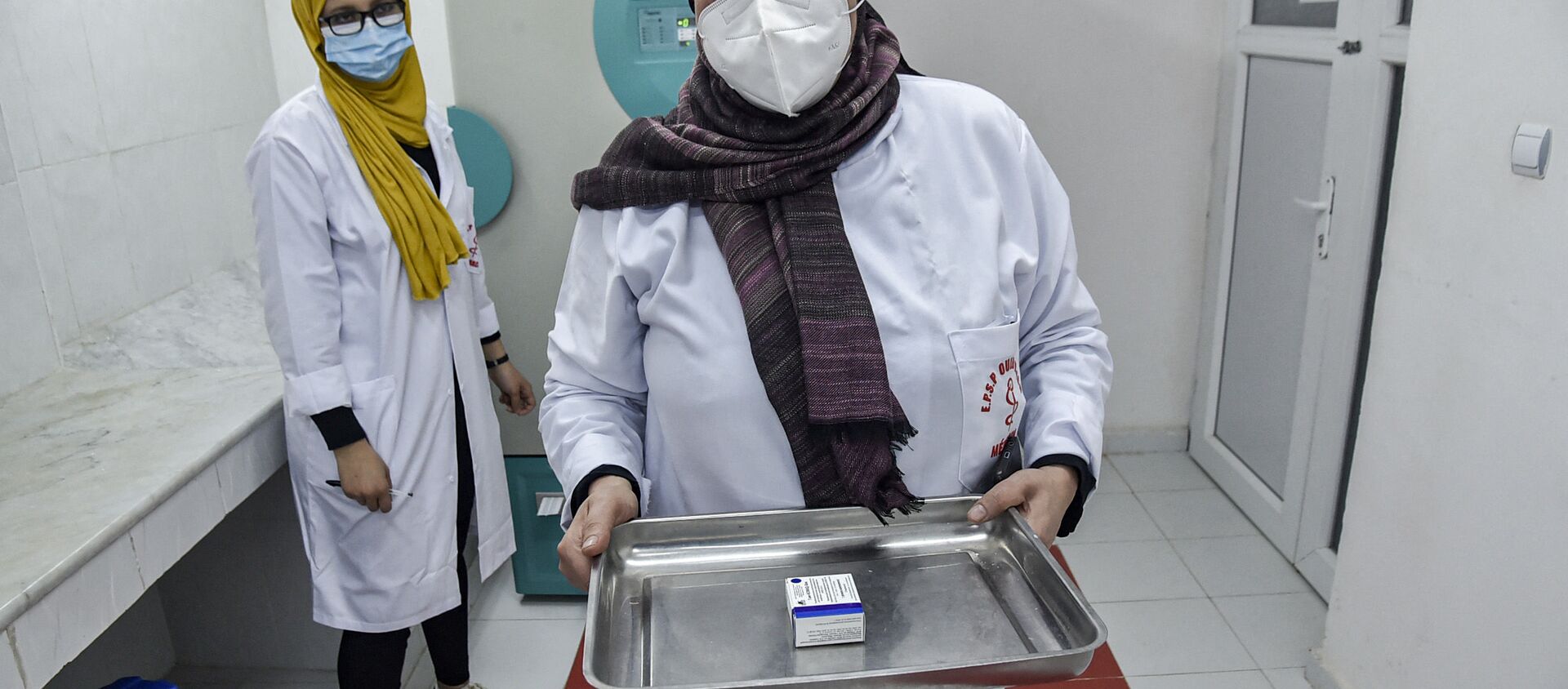 A medical worker walks with a pack of Russia's Sputnik V vaccine for COVID-19 coronavirus disease extracted from a refrigerator at a clinic in the city of Blida, about 45 kilometres southwest of the Algerian capital, on January 30, 2021, where the North African country is symbolically starting its vaccination drive at the same place to have registered the first novel coronavirus case in 2020. - Sputnik International, 1920