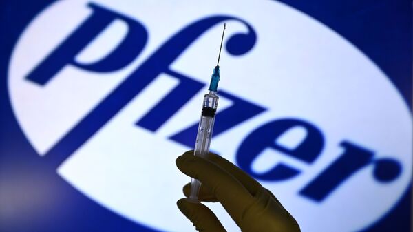 A syringe in front of the Pfizer logo. - Sputnik International