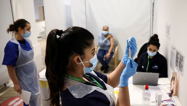 A person waits to get the coronavirus vaccine as a health worker prepares an injection with a dose, at a vaccination centre in Westfield Stratford City shopping centre, amid the outbreak of coronavirus disease (COVID-19), in London, Britain, February 18, 2021 - Sputnik International