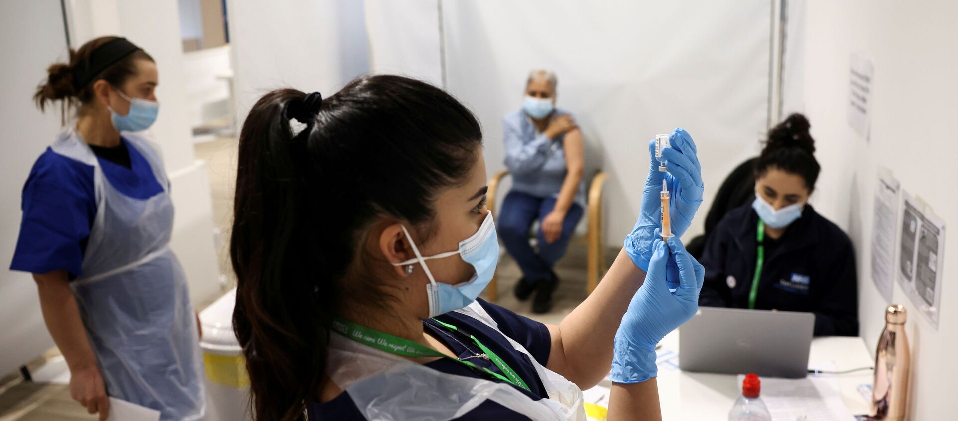 A person waits to get the coronavirus vaccine as a health worker prepares an injection with a dose, at a vaccination centre in Westfield Stratford City shopping centre, amid the outbreak of coronavirus disease (COVID-19), in London, Britain, February 18, 2021 - Sputnik International, 1920, 08.04.2021