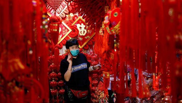  A vendor wearing a face mask following the coronavirus disease (COVID-19) outbreak uses her mobile phone at a market selling Spring Festival ornaments ahead of the Chinese Lunar New Year festivity, in Beijing, China January 27, 2021 - Sputnik International