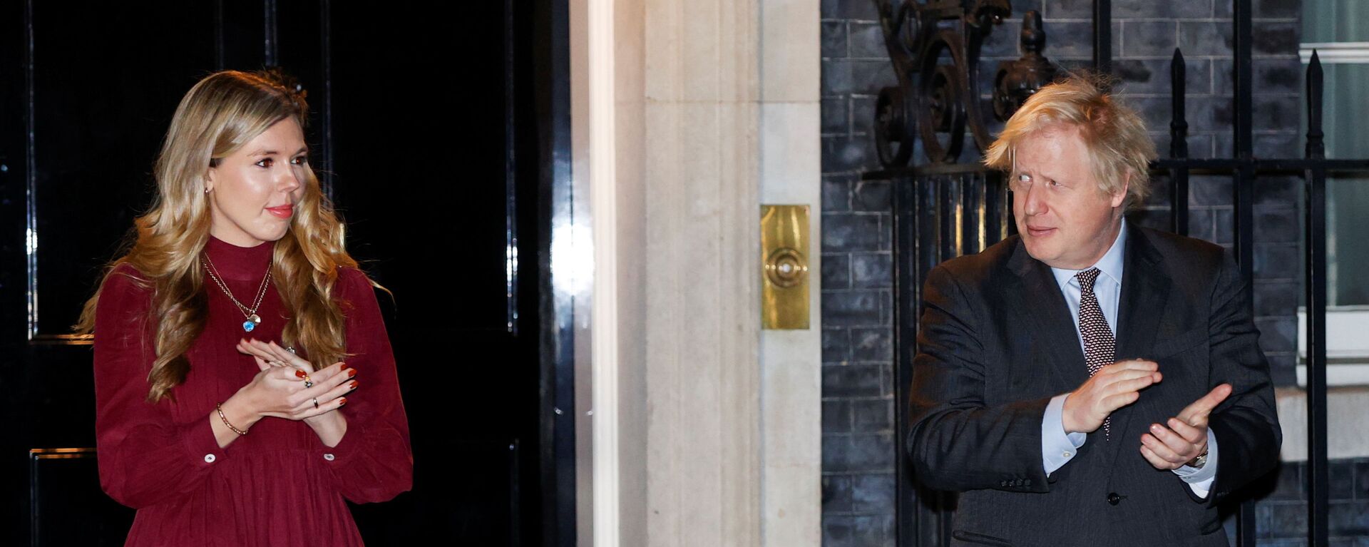 Britain's Prime Minister Boris Johnson and partner Carrie Symonds applaud outside 10 Downing Street during a national clap for late Captain Sir Tom Moore and NHS workers, amidst the coronavirus disease (COVID-19) outbreak, in London, Britain, February 3, 2021.  - Sputnik International, 1920, 29.04.2021