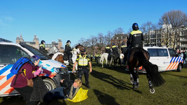 A woman lies on the ground after getting run down by a police officer on a horse, as people protest against the coronavirus disease (COVID-19) restrictions in Amsterdam, Netherlands, February 21, 2021.  - Sputnik International