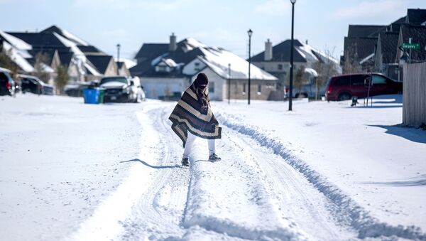 A man walks to his friend's home in a neighbourhood without electricity as snow covers the BlackHawk neighborhood in Pflugerville, Texas, U.S. February 15, 2021. Picture taken February 15, 2021 - Sputnik International