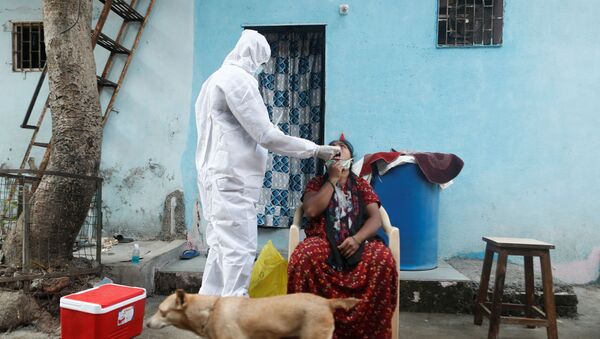 A healthcare worker in personal protective equipment (PPE) collects a swab sample from a resident during a testing campaign for the coronavirus disease (COVID-19), in Mumbai, India, February 23, 2021 - Sputnik International