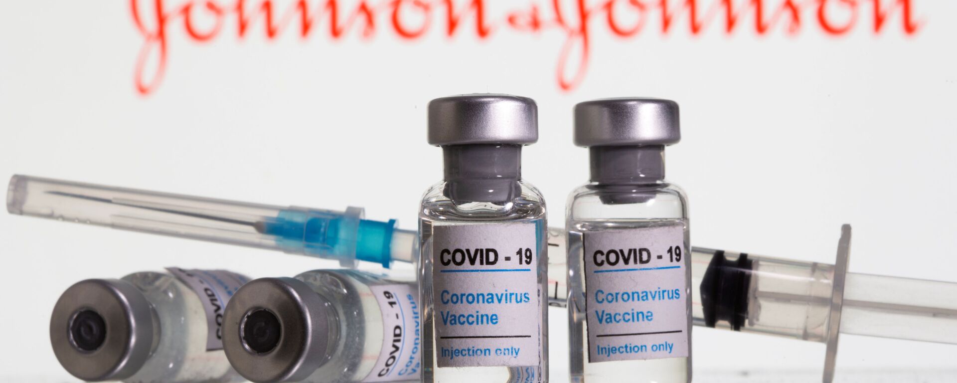 Vials labelled COVID-19 Coronavirus Vaccine and sryinge are seen in front of displayed Johnson&Johnson logo in this illustration taken, February 9, 2021 - Sputnik International, 1920