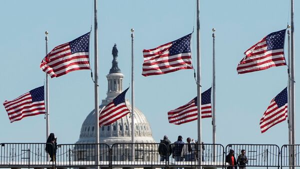 People walk past flags flying at half staff at the Washington Monument in memory of 500,000 deaths due to the coronavirus disease (COVID-19) in Washington, U.S., February 24, 2021.    - Sputnik International