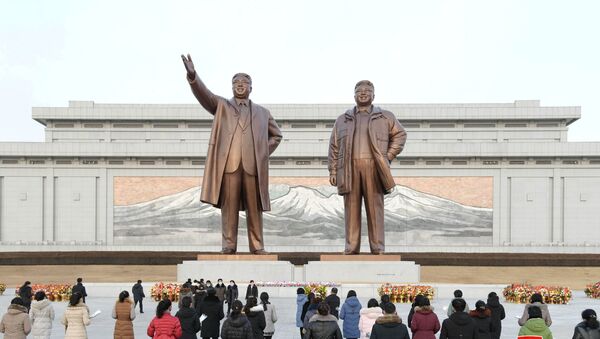 People lay floral tributes in front of the bronze statues of the late leaders Kim Il Sung and his son Kim Jong Il to commemorate the Day of the Shining Star, the birth anniversary of Kim Jong Il, at the Mansudae Grand Monument in Pyongyang, North Korea in this undated photo released by North Korea's Korean Central News Agency (KCNA) on February 17, 2021. - Sputnik International
