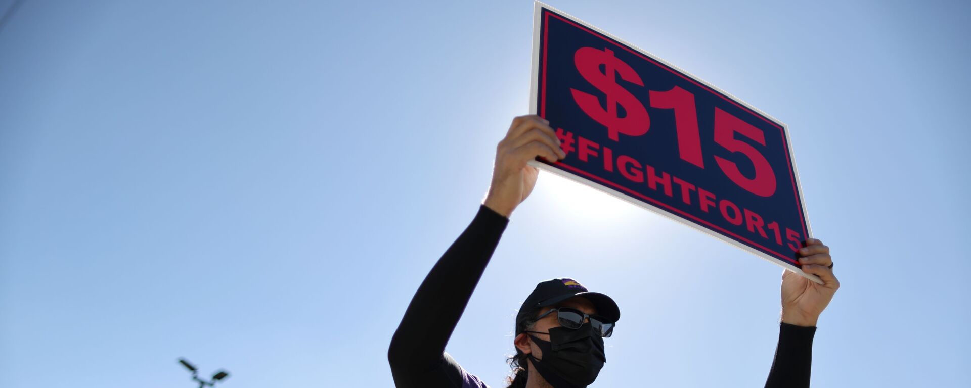 A man holds up a minimum wage sign at a rally held by fast food workers and supporters to celebrate the California Labor Commissioner’s order for the company to rehire and compensate workers who went on strike for coronavirus disease (COVID-19) protections, in Los Angeles, California, U.S., February 18, 2021. - Sputnik International, 1920, 27.02.2021