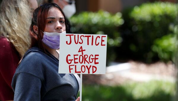 A protester holds a sign outside the Florida home of former Minneapolis police officer Derek Chauvin, who was recorded with his knee on the neck of African-American man George Floyd - Sputnik International