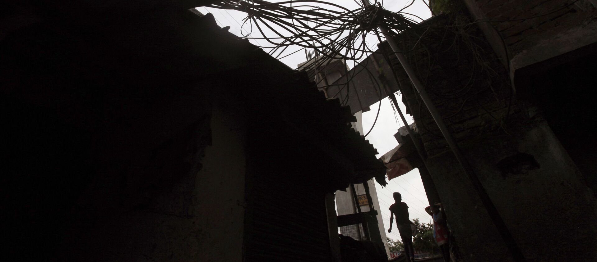 An Indian girl walks a narrow lane beneath a power pole with high-voltage cables coiling around at a slum in Mumbai, India, Friday, Aug. 3, 2012 - Sputnik International, 1920, 01.03.2021