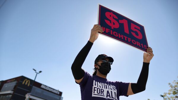 A man holds up a minimum wage sign at a rally held by fast food workers and supporters to celebrate the California Labor Commissioner’s order for the company to rehire and compensate workers who went on strike for coronavirus disease (COVID-19) protections, in Los Angeles, California, U.S., February 18, 2021. REUTERS/Lucy Nicholson - Sputnik International