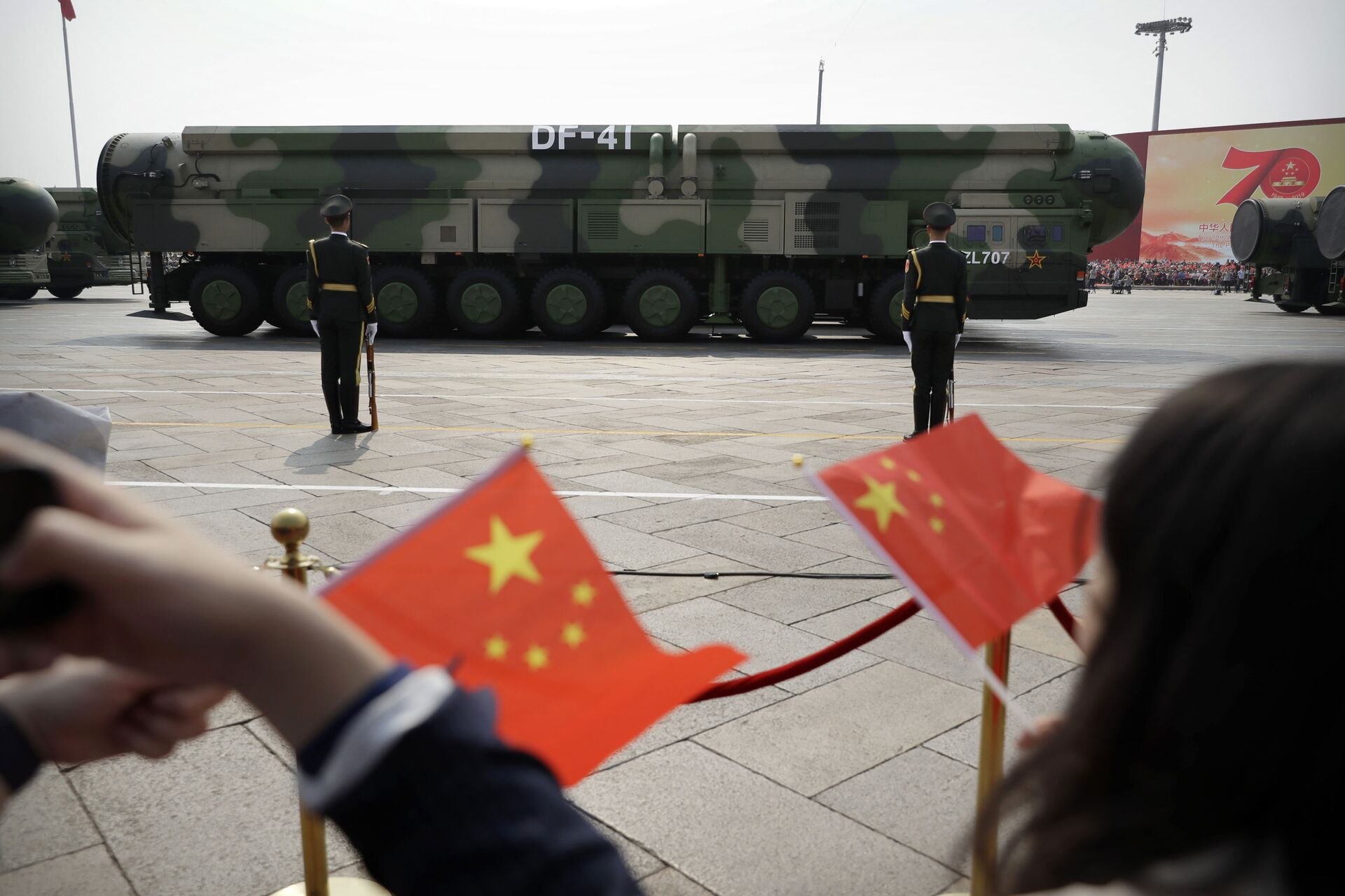 FILE - In this Oct. 1, 2019, file photo spectators wave Chinese flags as military vehicles carrying DF-41 ballistic missiles roll during a parade to commemorate the 70th anniversary of the founding of Communist China in Beijing. Trucks carrying weapons including a nuclear-armed missile designed to evade U.S. defenses rumbled through Beijing as the Communist Party celebrated its 70th anniversary in power - Sputnik International, 1920, 07.09.2021