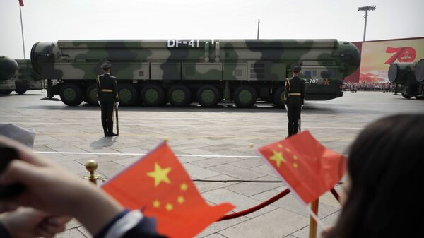 FILE - In this Oct. 1, 2019, file photo spectators wave Chinese flags as military vehicles carrying DF-41 ballistic missiles roll during a parade to commemorate the 70th anniversary of the founding of Communist China in Beijing. Trucks carrying weapons including a nuclear-armed missile designed to evade U.S. defenses rumbled through Beijing as the Communist Party celebrated its 70th anniversary in power - Sputnik International