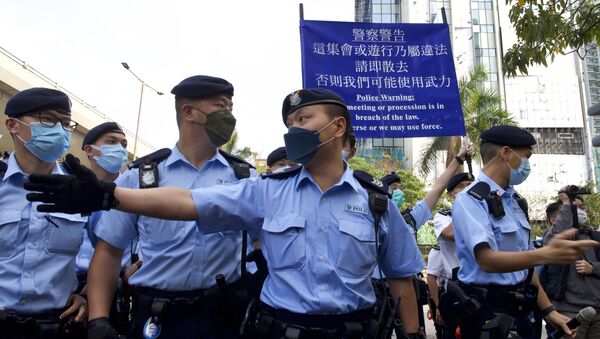 Police officers raise a warning flag against supporters gathered outside a court in Hong Kong Monday, March 1, 2021. Hong Kong police on Monday brought 47 pro-democracy activists to court on charges of conspiracy to commit subversion under the national security law imposed on the city by Beijing last year. - Sputnik International