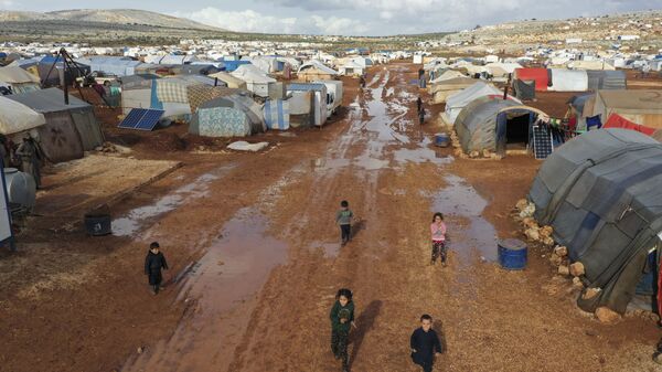 Syrian refugees walk through a camp for displaced muddied by recent rains near the village of Kafr Aruq , in Idlib province, Syria, Thursday, Jan. 28, 2021. - Sputnik International
