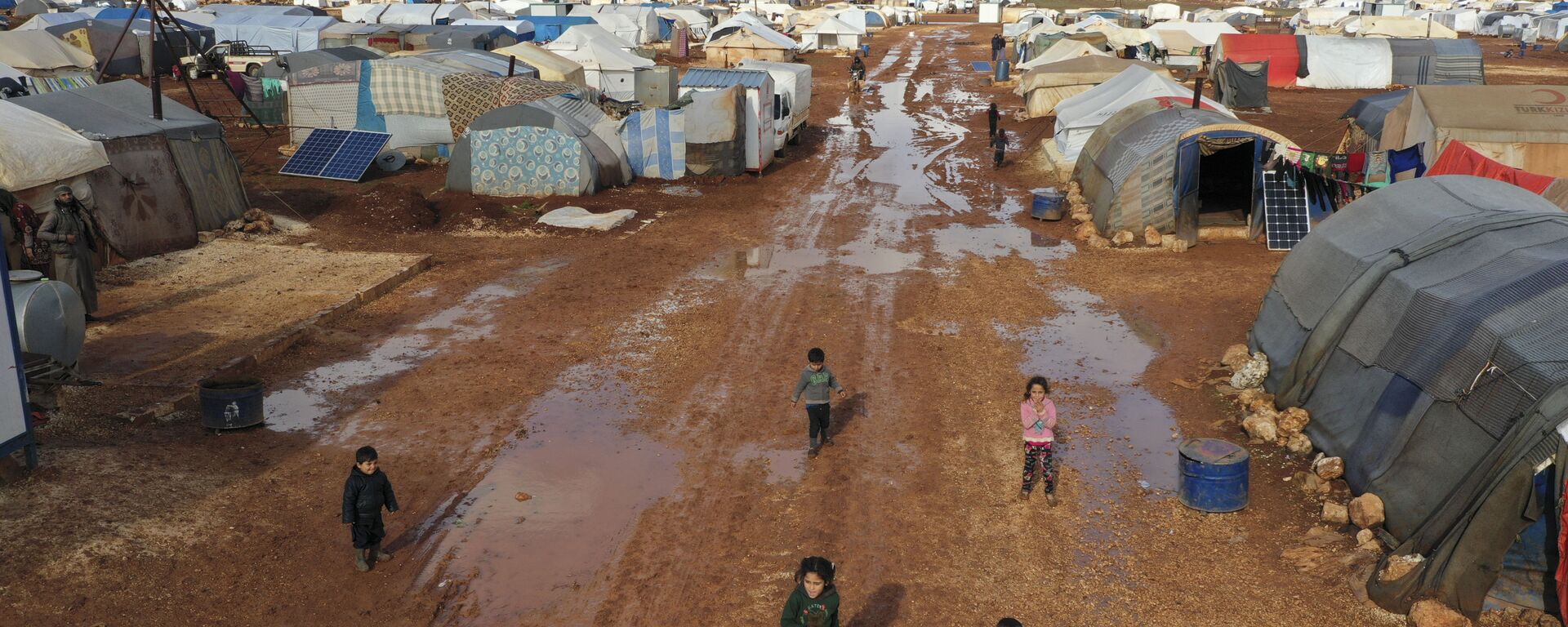 Syrian refugees walk through a camp for displaced muddied by recent rains near the village of Kafr Aruq , in Idlib province, Syria, Thursday, Jan. 28, 2021. - Sputnik International, 1920, 06.03.2021
