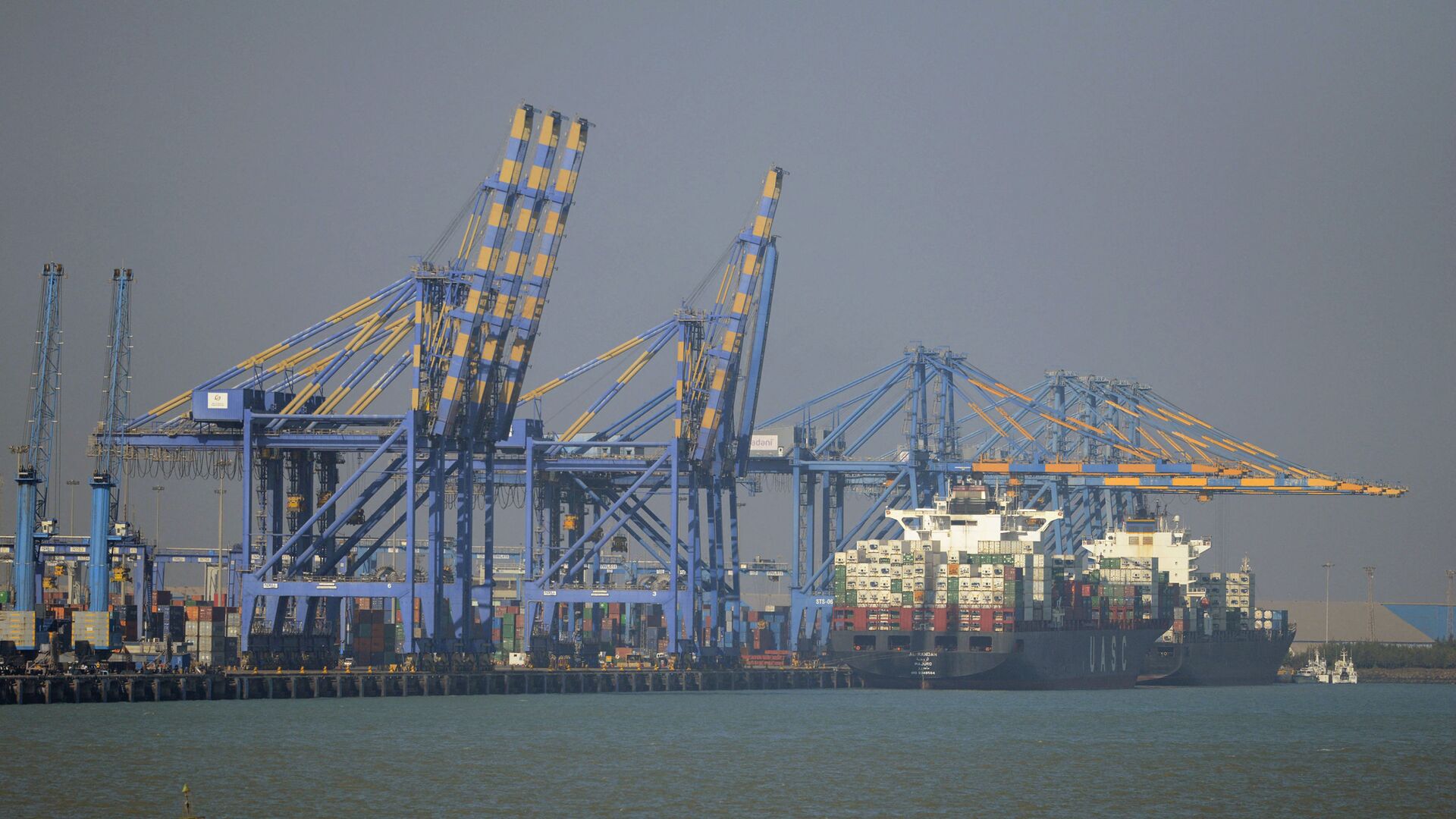 This photo taken on December 21, 2016 shows a container ship (R) docked at India's Adani Port Special Economic Zone (APSEZ) in Mundra - Sputnik International, 1920, 28.02.2022