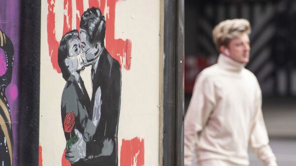 A man passes a poster showing a couple wearing protective face masks embracing in Shoreditch area of east London, following the introduction of measures to bring England out of the coronavirus lockdown, Thursday June 4, 2020 - Sputnik International