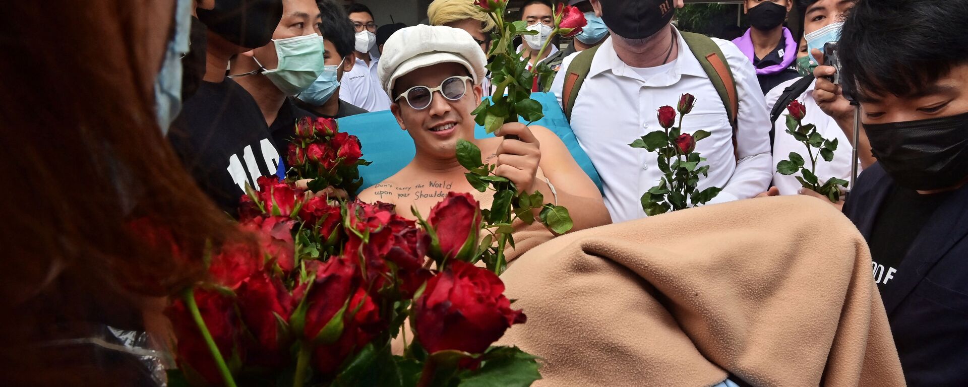 Anti-government blues musician Ammy The Bottom Blues receives flowers as he is wheeled on a hospital bed outside the Office of the Attorney General in Bangkok on February 17, 2021, before the state prosecutor decided whether to indict 18 activists on charges including sedition and lese majeste related to anti-government protests in 2020. - Sputnik International, 1920, 03.03.2021