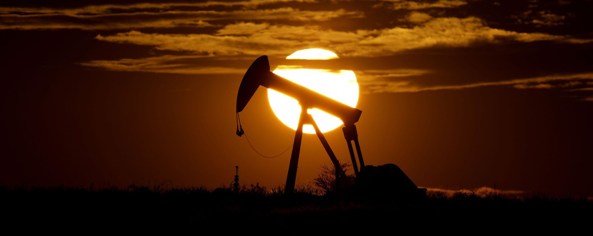 In this Wednesday, April 8, 2020, file photo, the sun sets behind an idle pump jack near Karnes City, Texas. Demand for oil continues to fall due to the new coronavirus outbreak. - Sputnik International, 1920, 17.02.2023