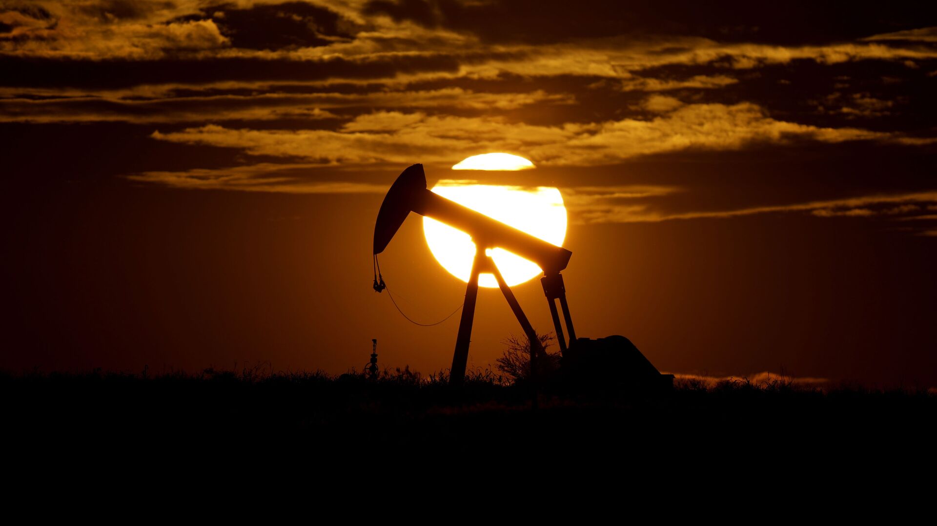 In this Wednesday, April 8, 2020, file photo, the sun sets behind an idle pump jack near Karnes City, Texas. Demand for oil continues to fall due to the new coronavirus outbreak. - Sputnik International, 1920, 04.03.2021