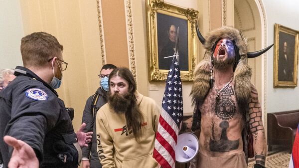 FILE - In this Wednesday, Jan. 6, 2021 file photo, supporters of President Donald Trump, including Jacob Chansley, right with fur hat, are confronted by U.S. Capitol Police officers outside the Senate Chamber inside the Capitol in Washington. Congress is set to hear from former security officials about what went wrong at the U.S. Capitol on Jan. 6. That's when when a violent mob laid siege to the Capitol and interrupted the counting of electoral votes. Three of the four testifying Tuesday resigned under pressure immediately after the attack, including the former head of the Capitol Police.  - Sputnik International