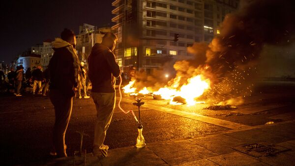 Protesters smoke water pipes in front burning tires that were set on fire to block a road, at Martyrs Square, in downtown Beirut, Lebanon, Saturday, March 6, 2021. - Sputnik International