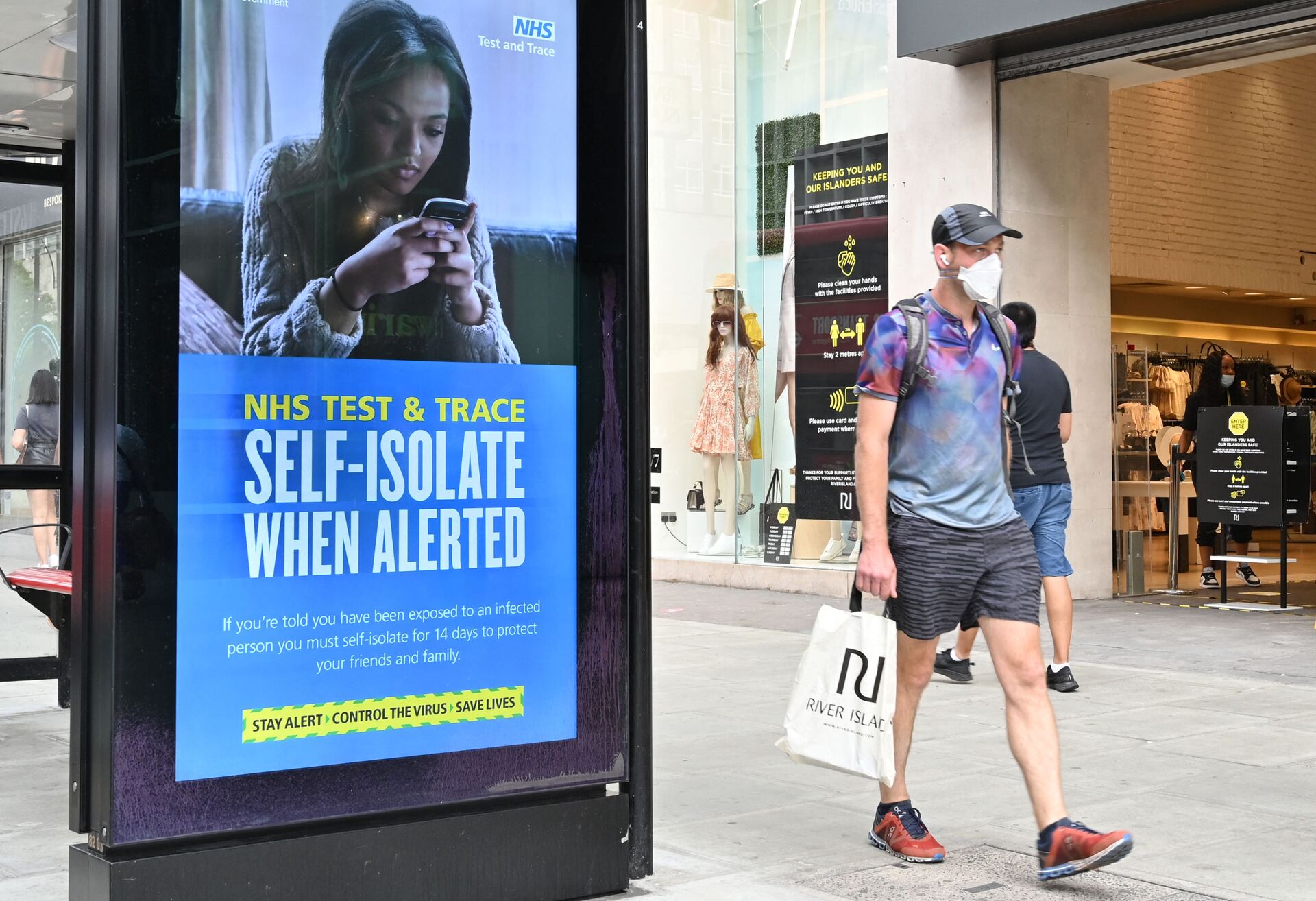 A shopper walks past an advertisment for the UK government's NHS Test and Trace system in Regent Street in London on June 15, 2020 as some non-essential retailers reopen from their coronavirus shutdown - Sputnik International, 1920, 07.09.2021