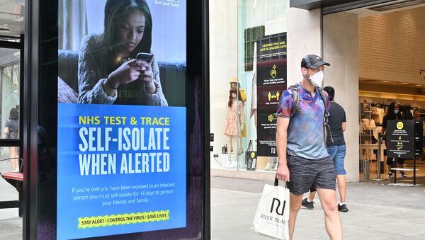A shopper walks past an advertisment for the UK government's NHS Test and Trace system in Regent Street in London on June 15, 2020 as some non-essential retailers reopen from their coronavirus shutdown - Sputnik International