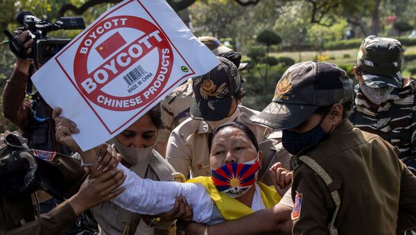 A Tibetan holds a placard as she is detained by police officers during a protest held to mark the 62nd anniversary of the Tibetan uprising against Chinese rule, outside the Chinese Embassy in New Delhi, India March 10, 2021 - Sputnik International