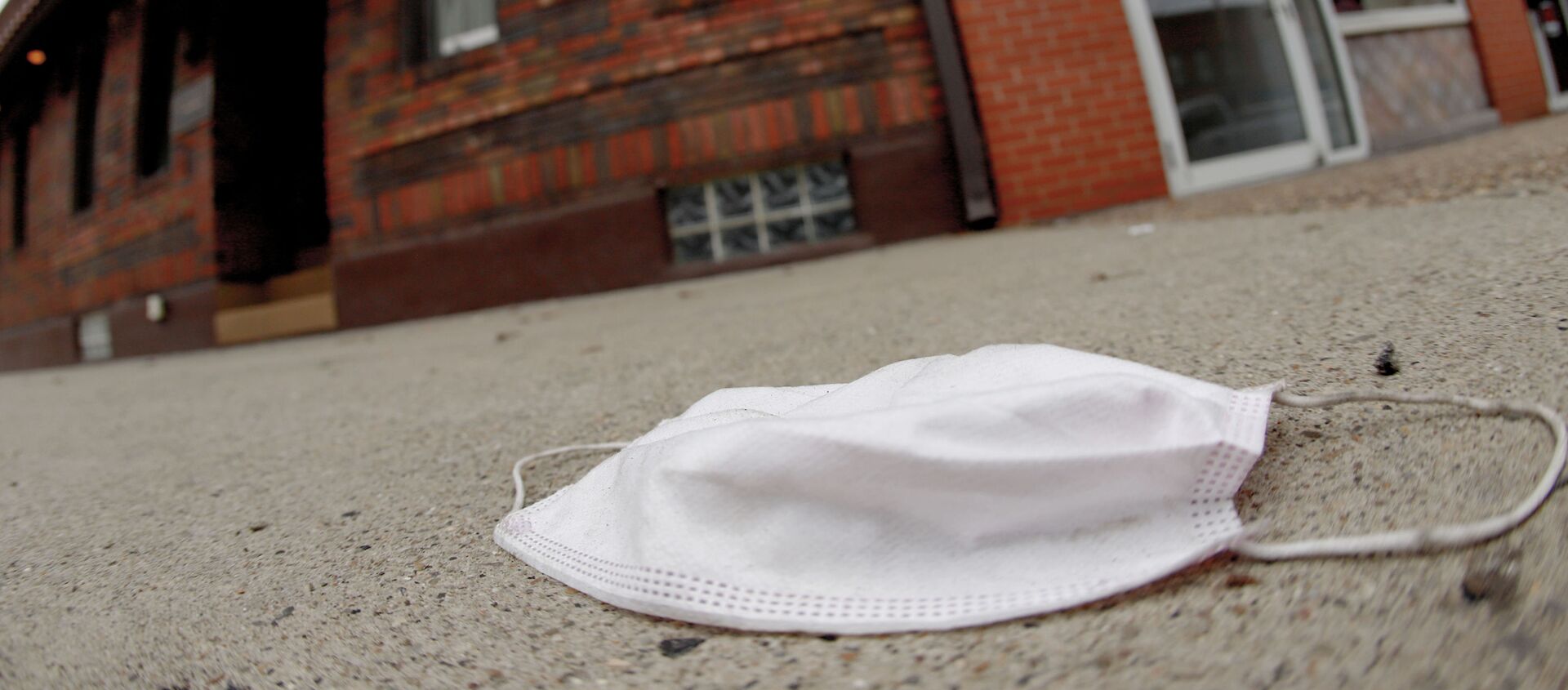 A discarded protective mask lays on the sidewalk along East Carson Street in the Southside neighborhood of Pittsburgh, Thursday, Jan. 7, 2021. - Sputnik International, 1920
