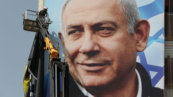 A labourer hangs a Likud party election campaign banner depicting party leader Israeli Prime Minister Benjamin Netanyahu, ahead of a March 23 ballot, in Jerusalem March 10, 2021 - Sputnik International