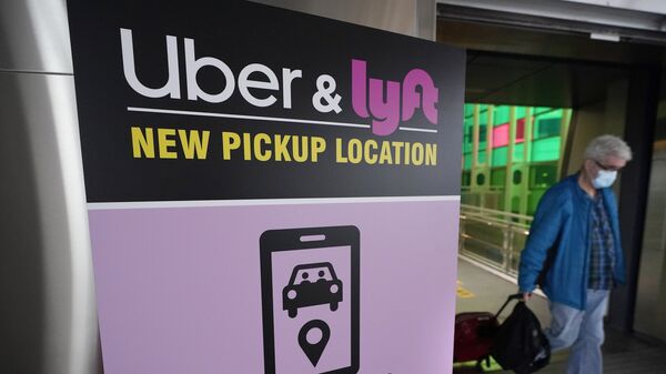 A passer-by pulls luggage while walking past a sign offering directions to an Uber and Lyft ride pickup location at Logan International Airport, in Boston, Tuesday, Feb. 9, 2021. Businesses like Uber, Airbnb and Square were born in recessions. Now, the effects of COVID-19 are forcing existing businesses to reinvent themselves, and some of today's most significant business obstacles will spark new startups offering innovative solutions. (AP Photo/Steven Senne) - Sputnik International