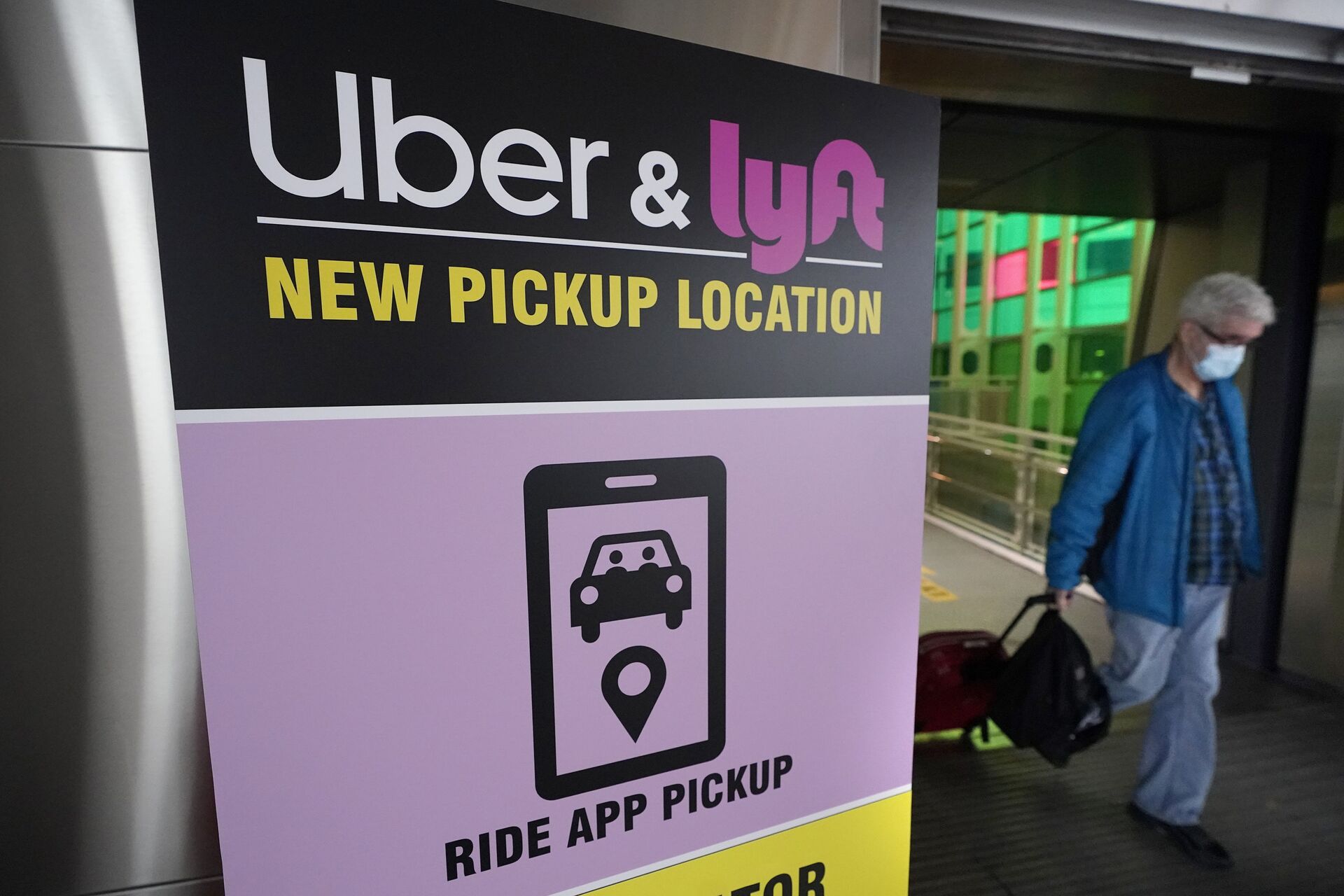 A passer-by pulls luggage while walking past a sign offering directions to an Uber and Lyft ride pickup location at Logan International Airport, in Boston, Tuesday, Feb. 9, 2021. Businesses like Uber, Airbnb and Square were born in recessions. Now, the effects of COVID-19 are forcing existing businesses to reinvent themselves, and some of today's most significant business obstacles will spark new startups offering innovative solutions. (AP Photo/Steven Senne) - Sputnik International, 1920, 07.09.2021