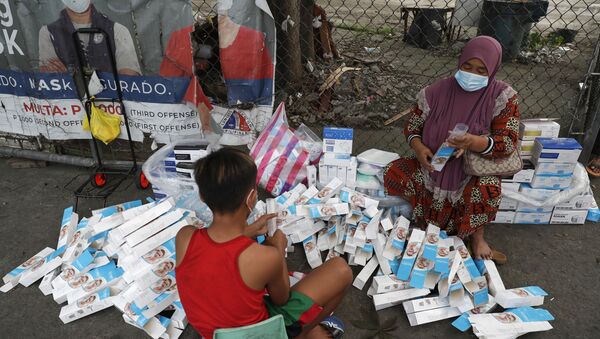 A woman and a boy wearing face masks to prevent the spread of the coronavirus arrange boxes of face shields in Manila, Philippines, Friday, March 12, 2021.  - Sputnik International