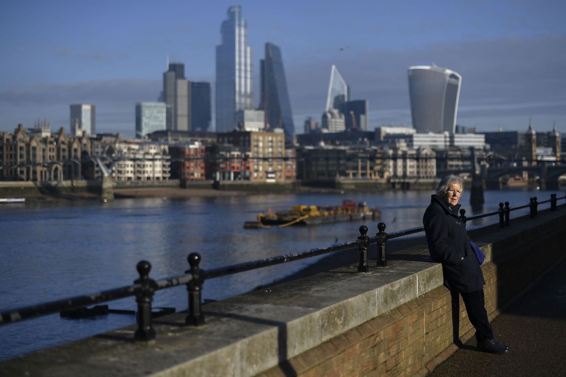 A woman rests in the sunshine on the south bank of River Thames with the skyline of the financial district called 'the City' in the background, in London, Tuesday, Dec. 8, 2020 - Sputnik International, 1920, 07.09.2021
