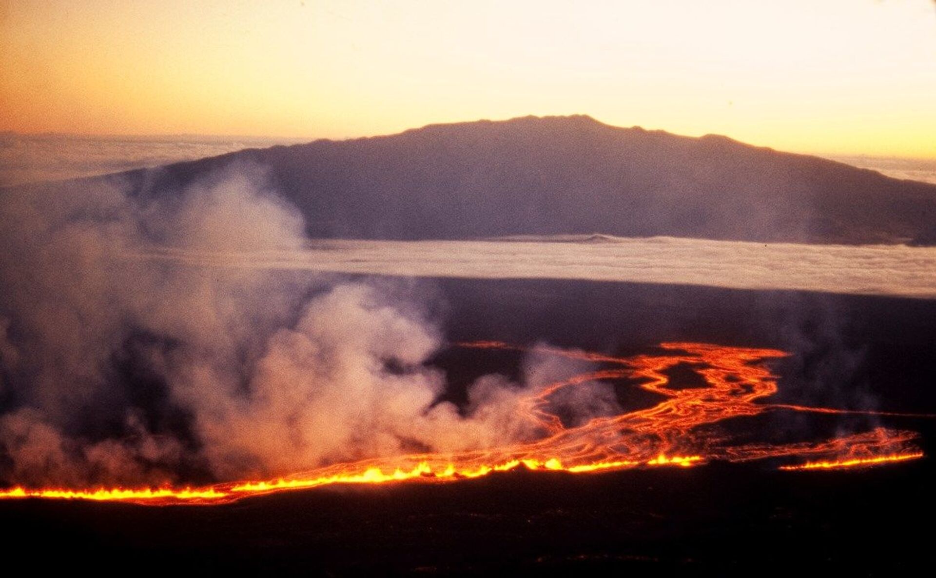 The sun rises beyond Mauna Kea as lava flows down the side of Mauna Loa on the morning of July 6th, 1975 - Sputnik International, 1920, 21.08.2022