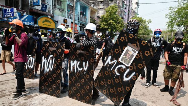 Demonstrators stand behind makeshift shields during an anti-coup protest in Yangon - Sputnik International