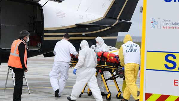 A patient suffering from a severe form of Covid-19 is carried into a plane by health workers prior to his transfer to a hospital in Bordeaux, on March 14, 2021 in Orly, as Paris' region intensive care units are overloaded with Covid-19 patients. - Sputnik International
