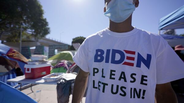A Honduran man seeking asylum in the United States wears a shirt that reads, Biden please let us in, as he stands among tents that line an entrance to the border crossing, Monday, March 1, 2021, in Tijuana, Mexico. - Sputnik International