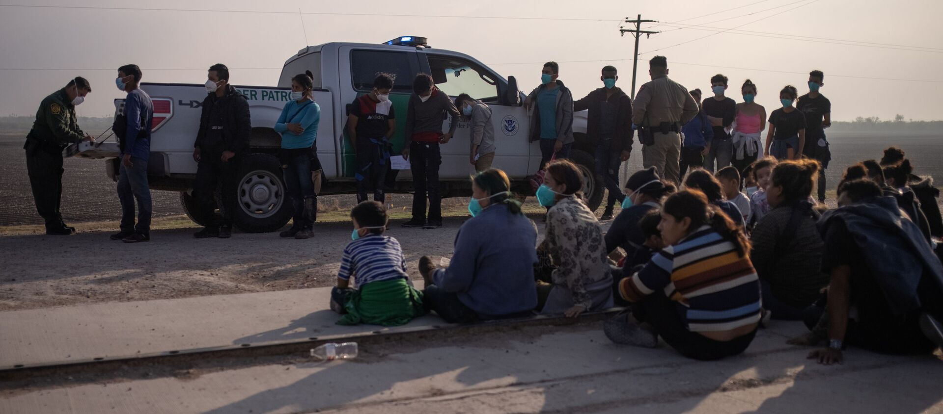 A U.S. Border Patrol agent processes asylum-seeking unaccompanied minors as family units sit on the sideline after about 70 migrants crossed the Rio Grande river into the United States from Mexico on a raft in Penitas, Texas, U.S., March 17, 2021. - Sputnik International, 1920, 22.03.2021