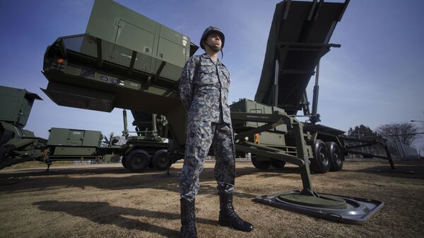 A member of Japan Ground Self-Defense Force stands guard next to a surface-to-air Patriot Advanced Capability-3 (PAC-3) missile interceptor launcher vehicle - Sputnik International