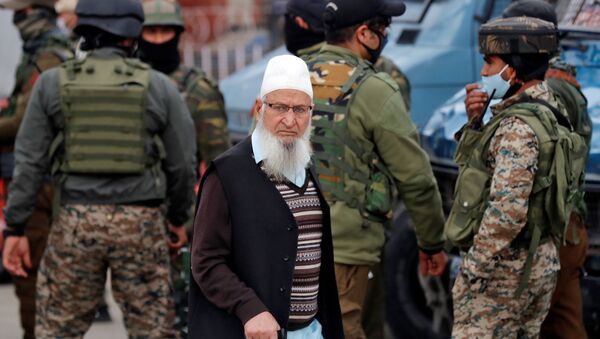 A Kashmiri Muslim man walks past Indian security force personnel standing guard during a cordon and search operation, in Srinagar February 26, 2021 - Sputnik International