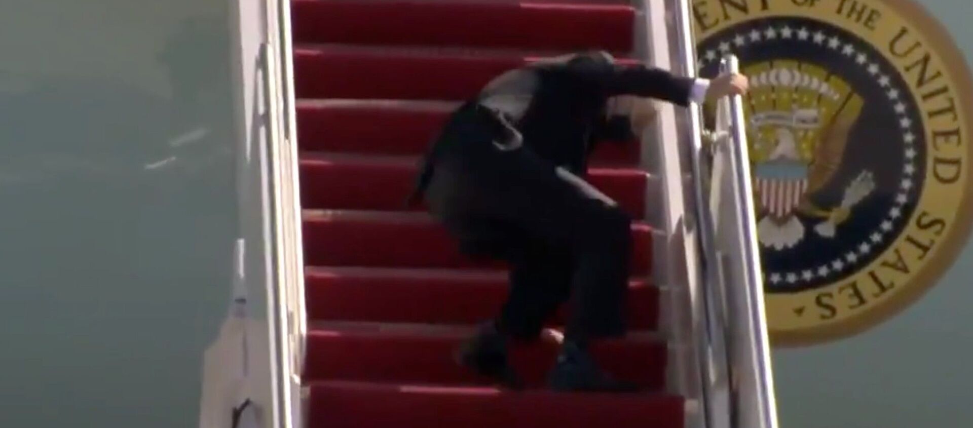 Screenshot captures the moment that US President Joe Biden caught himself after stumbling three times while ascending the airstairs to board Air Force Once. - Sputnik International, 1920, 21.03.2021