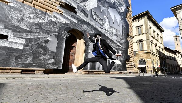 French contemporary artist JR jumps in front of his art installation on the facade of Strozzi Palace titled 'La Ferita (The Wound)', and showing an optical illusion of a black and white interior of the elegant Renaissance palace, as the artist efforts to make a statement on accessibility to culture in the coronavirus disease (COVID-19) era, in Florence, Italy, March 19, 2021. - Sputnik International