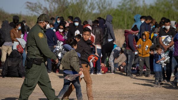 A U.S. Border Patrol Agent escorts two asylum-seeking unaccompanied minors from Central America as others take refuge near a baseball field after crossing the Rio Grande river into the United States from Mexico on rafts, in La Joya, Texas, U.S., March 19, 2021. - Sputnik International