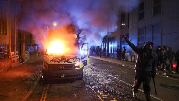 A demonstrator gestures near a burning police vehicle during a protest against a new proposed policing bill, in Bristol, Britain, March 21, 2021. - Sputnik International