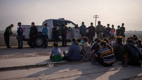 A U.S. Border Patrol agent processes asylum-seeking unaccompanied minors as family units sit on the sideline after about 70 migrants crossed the Rio Grande river into the United States from Mexico on a raft in Penitas, Texas, U.S., March 17, 2021. - Sputnik International